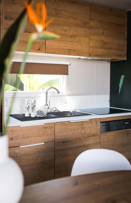 Cucina moderna, calda, con mobili in legno e luce naturale.